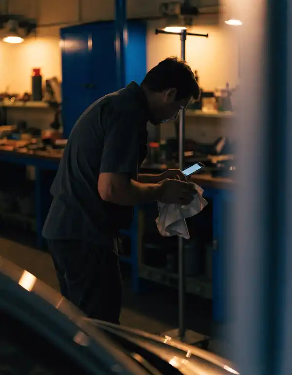 A mechanic checking a booking on a phone in the shop